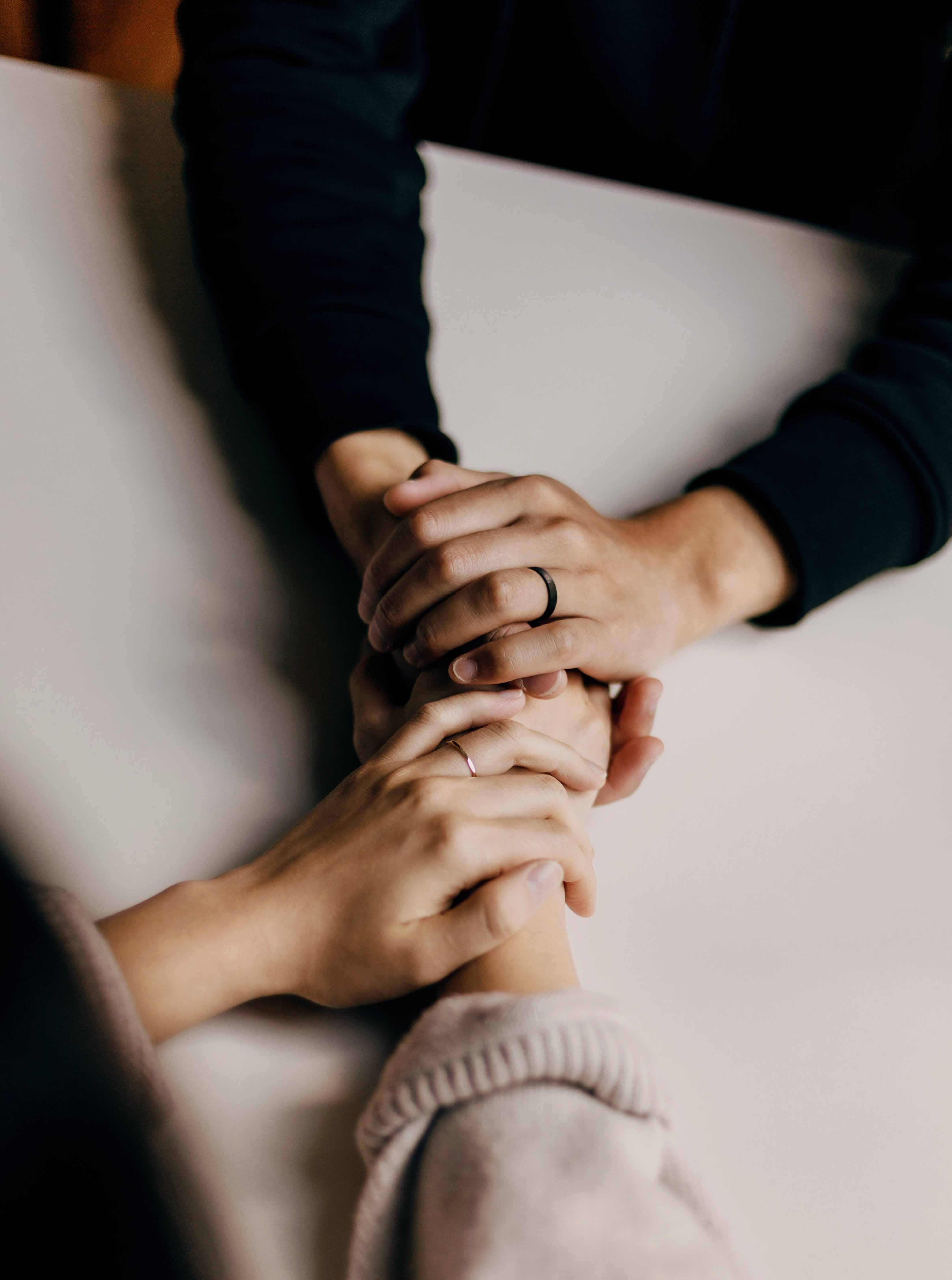 Two people sitting at a table in front of each other holding hands